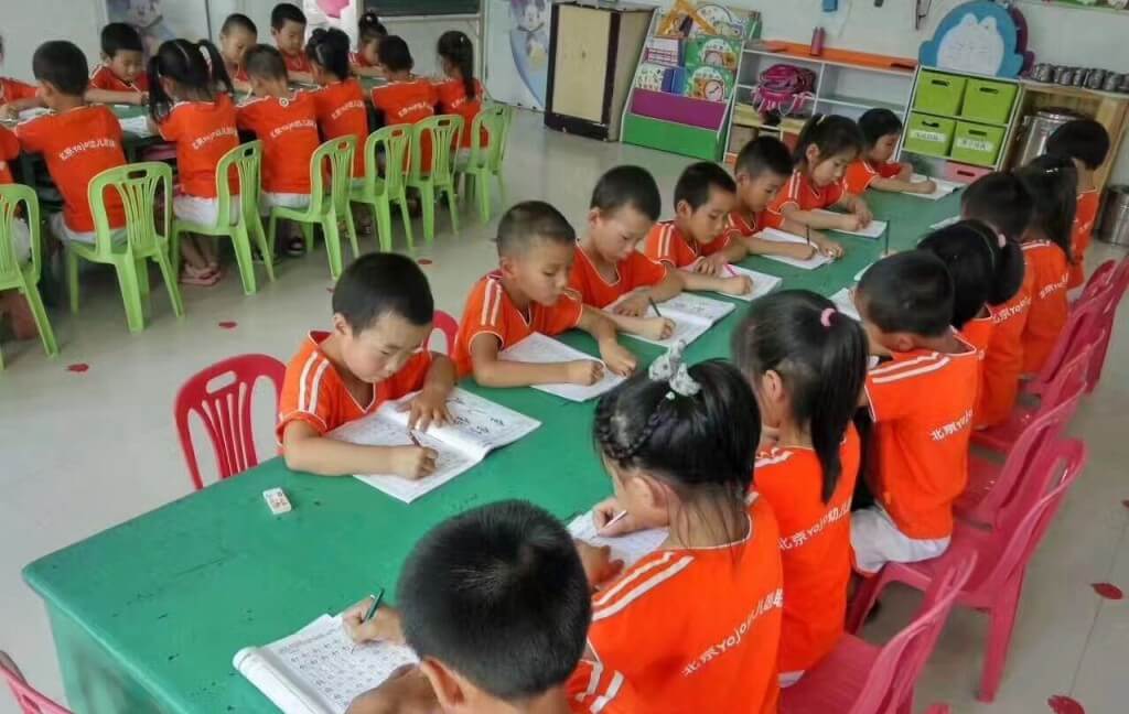 Niños sentados derechos en la sala de jardín infantil